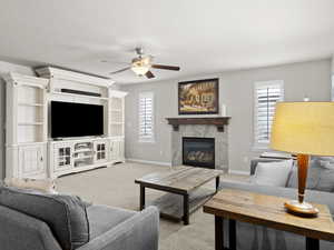 Living area featuring a high end fireplace, light colored carpet, and baseboards