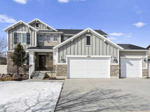 Craftsman house featuring board and batten siding, concrete driveway, stone siding, and an attached garage