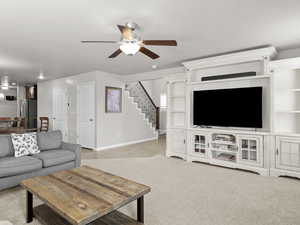 Living room with ceiling fan, baseboards, and stairs