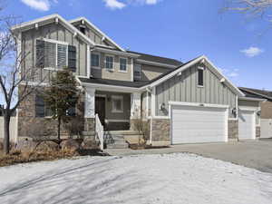 Craftsman house with board and batten siding, stone siding, a garage, and concrete driveway