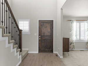 Foyer entrance featuring stairs, wood finished floors, visible vents, and baseboards