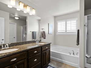 Bathroom with double vanity, a garden tub, a sink, and a stall shower