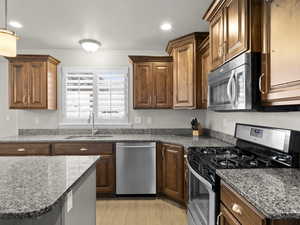 Kitchen with brown cabinets, stainless steel appliances, recessed lighting, a sink, and light wood-type flooring