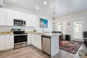 Kitchen with a peninsula, a sink, visible vents, appliances with stainless steel finishes, and a wood stove