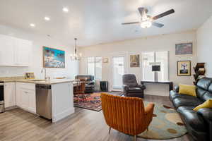 Living room featuring recessed lighting, visible vents, baseboards, light wood-style flooring, and ceiling fan with notable chandelier