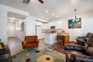 Living area featuring recessed lighting, visible vents, light wood-style floors, baseboards, and ceiling fan with notable chandelier