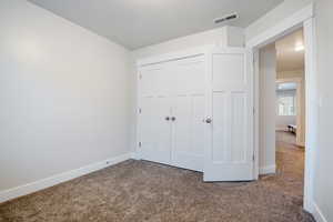 Unfurnished bedroom with carpet, a closet, visible vents, and baseboards