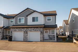 View of front of home with board and batten siding, driveway, a shingled roof, and an attached garage