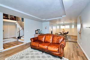 Living area with visible vents, stairway, a textured ceiling, and wood finished floors