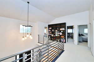 Hall featuring lofted ceiling, carpet floors, and an upstairs landing