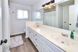 Full bath featuring double vanity, wood finished floors, a sink, and visible vents