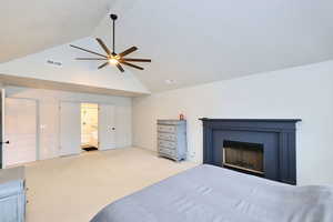 Bedroom featuring carpet floors, a fireplace, visible vents, ensuite bathroom, and high vaulted ceiling