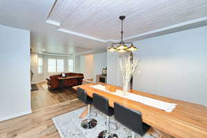 Dining space featuring baseboards, a raised ceiling, wooden ceiling, wood finished floors, and a textured ceiling