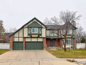 English style home featuring concrete driveway, a front lawn, fence, and stucco siding