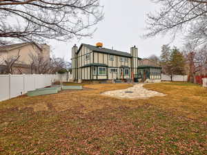 Rear view of property featuring a vegetable garden, a sunroom, a fenced backyard, a chimney, and board and batten siding