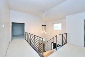 Corridor with lofted ceiling and an upstairs landing