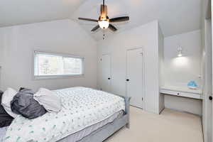 Bedroom with light carpet, vaulted ceiling, and a ceiling fan