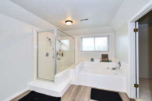 Bathroom with visible vents, a stall shower, a textured ceiling, wood finished floors, and a bath