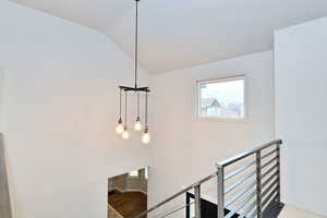 Stairway featuring plenty of natural light, vaulted ceiling, and baseboards