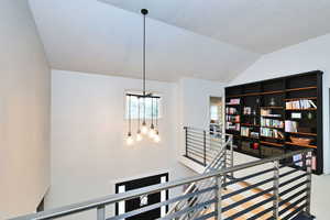 Stairs featuring vaulted ceiling and a notable chandelier