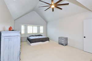 Bedroom with a ceiling fan, lofted ceiling, and light carpet