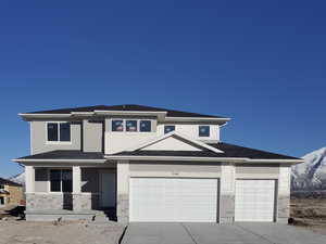 Prairie-style home with an attached garage, stone siding, a mountain view, 3 car garage, and concrete driveway