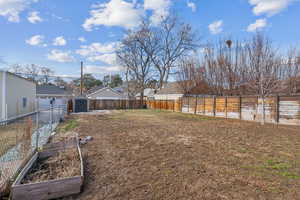 View of yard featuring a garden, a residential view, a storage unit, fence.