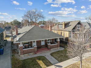 View of front of house featuring a residential view, covered porch, roof with shingles, and brick siding