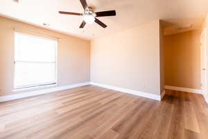 Spare room featuring light wood finished floors, visible vents, and baseboards