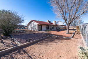 Rear view of house with a chimney, stucco siding, central AC, fence, and a tiled roof