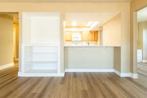 Kitchen with white microwave, a kitchen bar, and light wood-style flooring