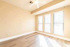 Spare room featuring ceiling fan, light wood finished floors, visible vents, and baseboards