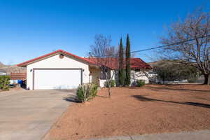 View of front of house with driveway, a tile roof, a garage, and stucco siding