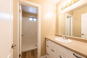 Full bath featuring a walk in shower, toilet, wood finished floors, and vanity