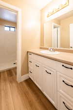 Bathroom featuring toilet, wood finished floors, vanity, baseboards, and walk in shower