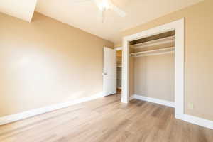 Unfurnished bedroom with baseboards, ceiling fan, a closet, and light wood-style floors