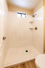 Full bath featuring a shower, a textured ceiling, toilet, and wood finished floors