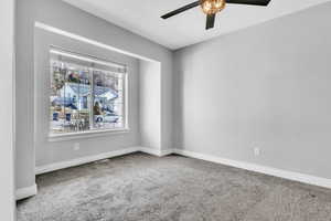 Carpeted empty room featuring visible vents, baseboards, and a ceiling fan