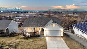 View of front of home featuring a garage, a shingled roof, a yard, a mountain view, and a porch