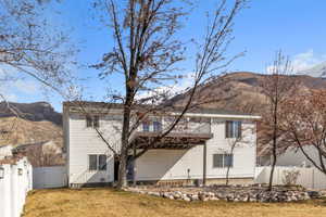 Rear view of property featuring a yard, a gate, fence, and a mountain view