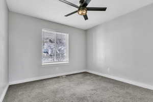 Carpeted empty room with a ceiling fan, visible vents, and baseboards