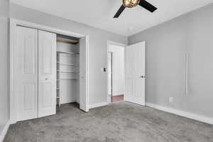 Unfurnished bedroom featuring carpet floors, a closet, baseboards, and a ceiling fan