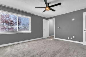 Unfurnished bedroom with a textured ceiling, ceiling fan, carpet flooring, and baseboards