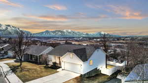 View of front of property featuring fence, a mountain view, concrete driveway, and roof with shingles