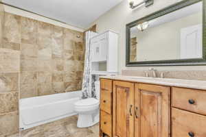 Bathroom featuring shower / bath combination with curtain, vanity, and toilet