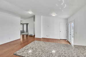 Interior space featuring lofted ceiling, visible vents, baseboards, and wood finished floors