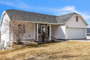 Ranch-style house with a garage, a front yard, and roof with shingles