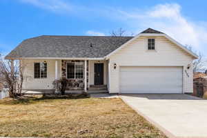 View of front of home featuring a front yard, concrete driveway, roof with shingles, and covered porch