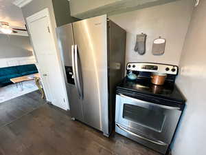 Kitchen featuring ceiling fan, stainless steel appliances, dark wood-style flooring, and wainscoting