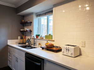 Kitchen featuring crown molding, black dishwasher, light countertops, and a sink